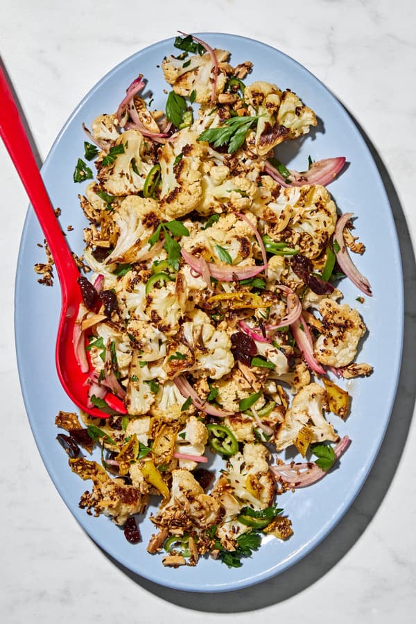 Roasted cauliflower salad with herbs, almonds, dried cherries, and spices on a serving plate.