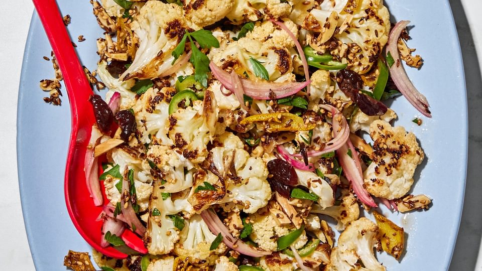 Roasted cauliflower salad with herbs, almonds, dried cherries, and spices on a serving plate.