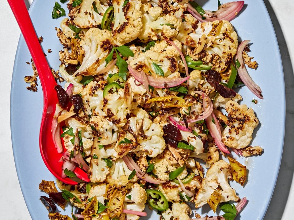 Roasted cauliflower salad with herbs, almonds, dried cherries, and spices on a serving plate.