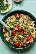 Italian sausage, cabbage, and white bean skillet served in a bowl with cherry tomatoes and fresh herbs, hearty one-pan dinner
