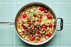 Italian sausage, cabbage, and white bean skillet served in a bowl with cherry tomatoes and fresh herbs, easy 20 minute recipe