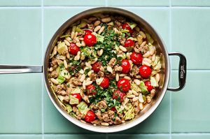 Italian sausage, cabbage, and white bean skillet served in a bowl with cherry tomatoes and fresh herbs, easy one pan dinner