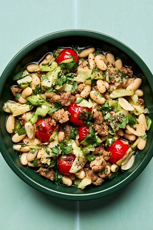 Italian sausage, cabbage, and white bean skillet served in a bowl with cherry tomatoes and fresh herbs, easy 20 minute recipe