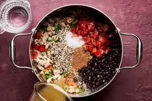Southwest turkey & quinoa soup cooking in a pot with ingredients like black beans, fire roasted tomatoes and bell peppers
