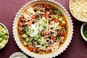 Bowl of Healthy Southwest turkey quinoa soup topped with sour cream, avocado, cilantro, and green onion. A hearty dinner.