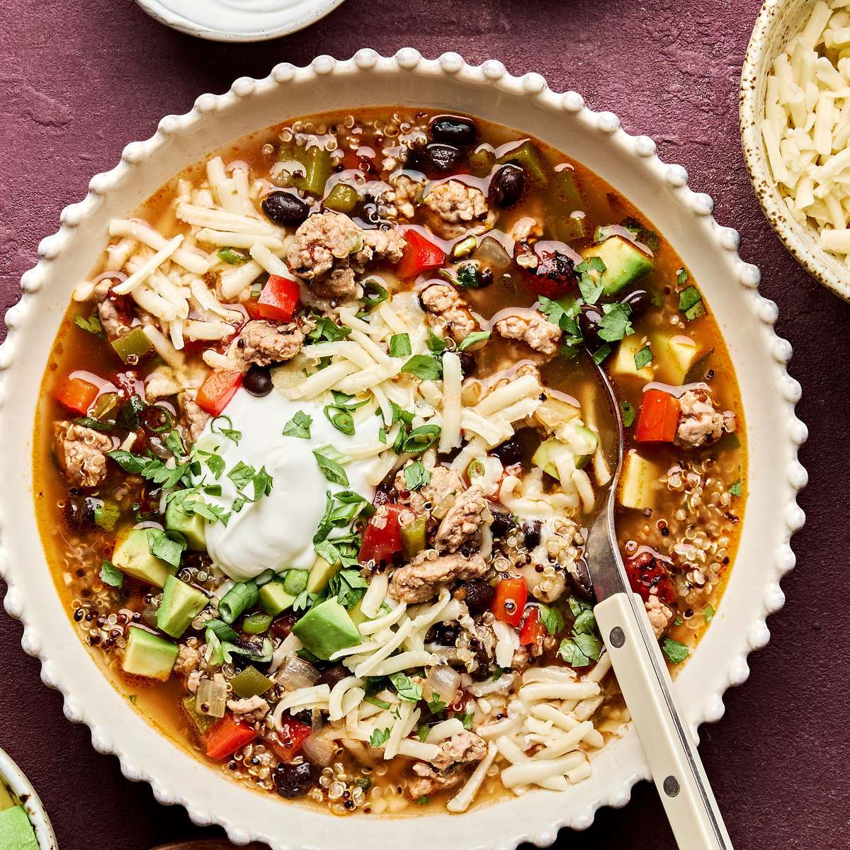 Bowl of Healthy Southwest turkey quinoa soup topped with sour cream, avocado, cilantro, and green onion. A hearty dinner.