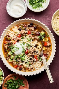 Bowl of Healthy Southwest turkey quinoa soup topped with sour cream, avocado, cilantro, and green onion. A hearty dinner.