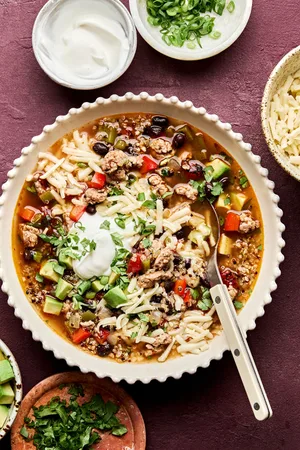 Bowl of Healthy Southwest turkey quinoa soup topped with sour cream, avocado, cilantro, and green onion. A hearty dinner.