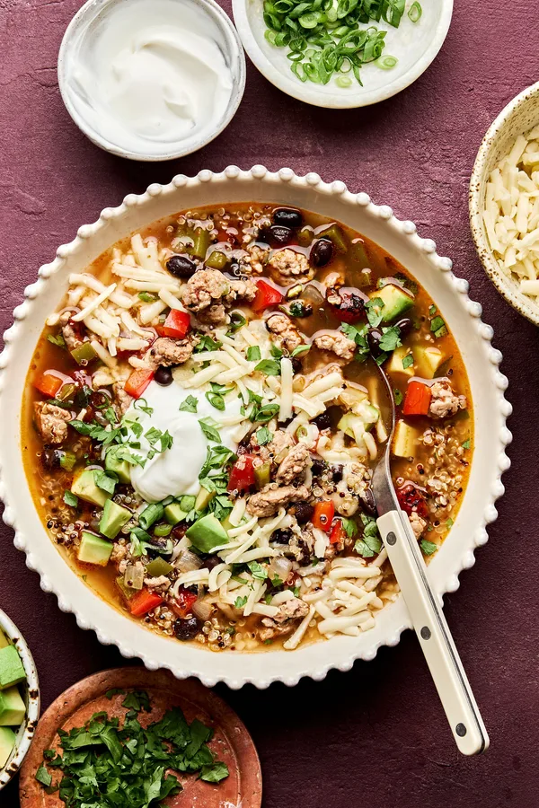 Bowl of Healthy Southwest turkey quinoa soup topped with sour cream, avocado, cilantro, and green onion. A hearty dinner.