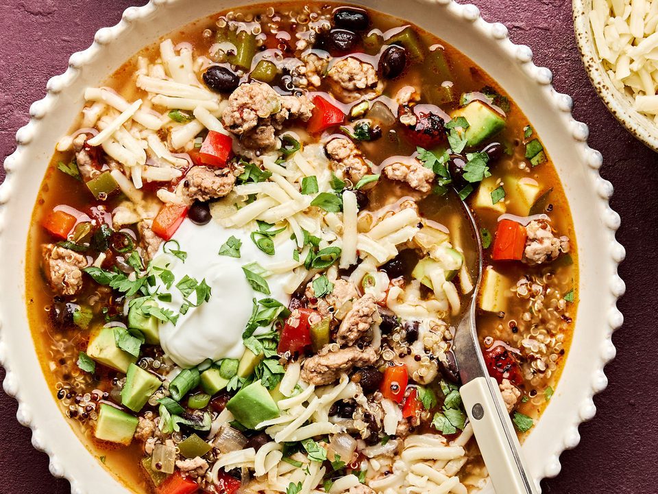 Bowl of Healthy Southwest turkey quinoa soup topped with sour cream, avocado, cilantro, and green onion. A hearty dinner.