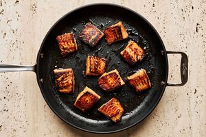 teriyaki marinated salmon being cooked in a skillet