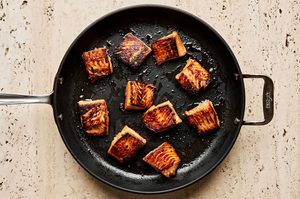 teriyaki marinated salmon being cooked in a skillet
