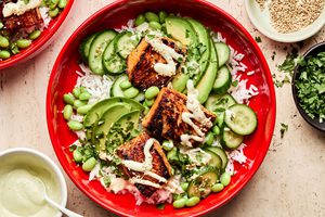 Teriyaki Salmon Bowl with coconut rice, edamame, cucumbers, avocado, cilantro and sesame seeds drizzled with wasabi dressing