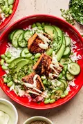 Teriyaki Salmon Bowl with coconut rice, edamame, cucumbers, avocado, cilantro and sesame seeds drizzled with wasabi dressing