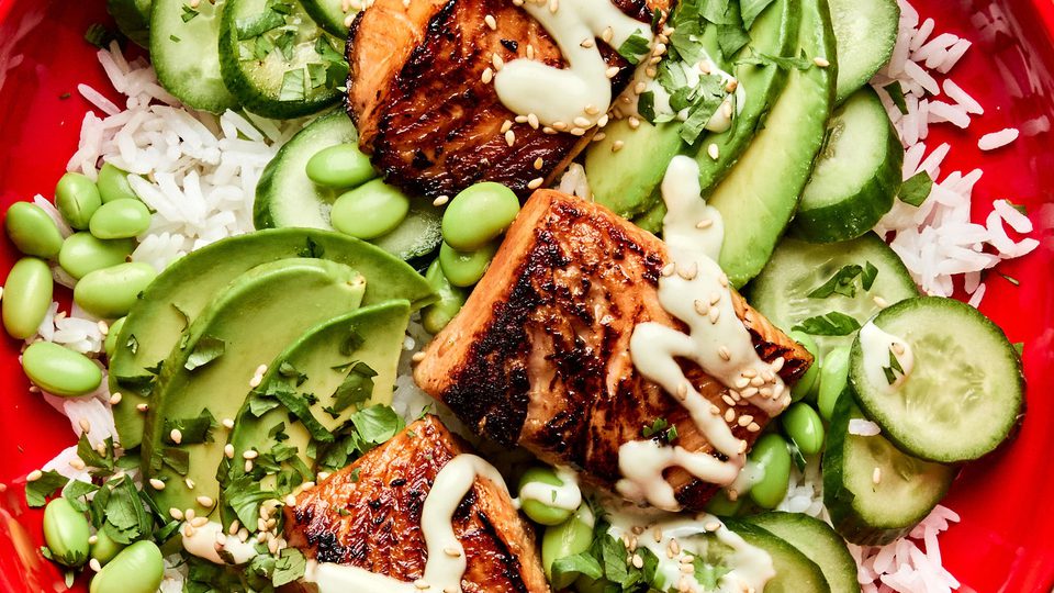 Teriyaki Salmon Bowl with coconut rice, edamame, cucumbers, avocado, cilantro and sesame seeds drizzled with wasabi dressing