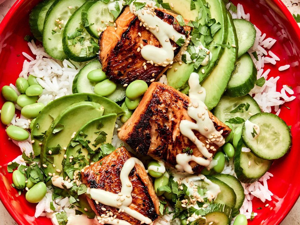 Teriyaki Salmon Bowl with coconut rice, edamame, cucumbers, avocado, cilantro and sesame seeds drizzled with wasabi dressing