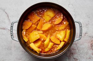 garlic, ginger, onions, red curry paste, pumpkin, squash, stock and salt being boiled in a pot to make Thai pumpkin soup