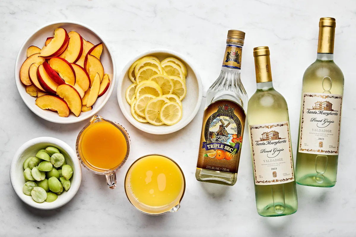 white wine, orange juice, triple sec, peach nectar, peaches, lemons and grapes set out to make white sangria