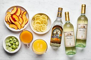 white wine, orange juice, triple sec, peach nectar, peaches, lemons and grapes set out to make white sangria