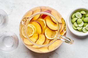 sliced peaches and lemons added to a pitcher with wine, orange juice, triple sec, and peach nectar