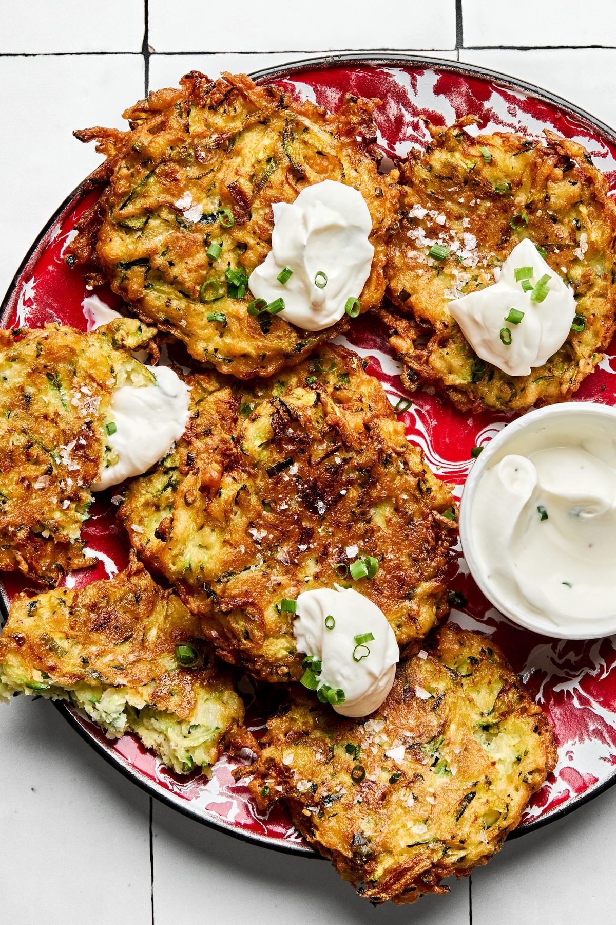 golden-brown homemade zucchini fritters with perfectly crispy on the edges on a plate served with sour cream