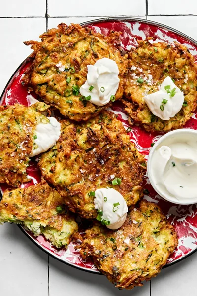 golden-brown homemade zucchini fritters with perfectly crispy on the edges on a plate served with sour cream