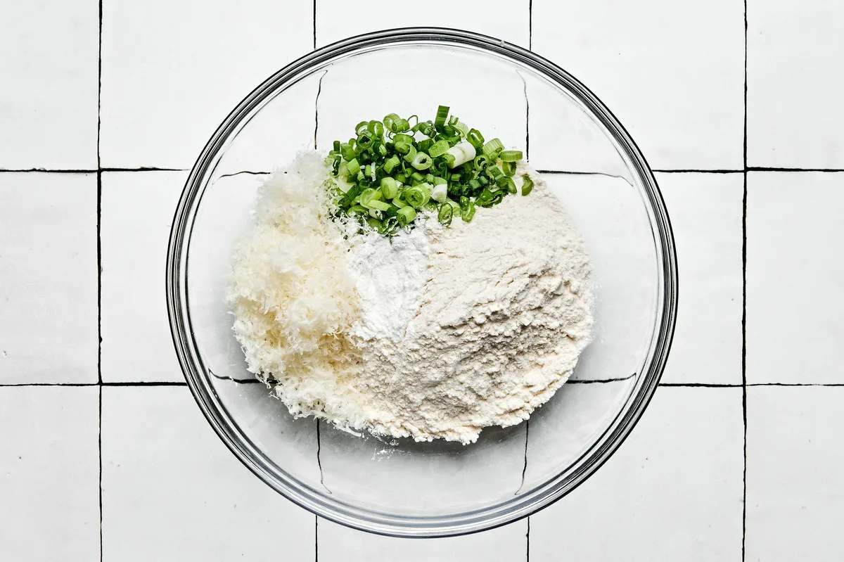 flour, baking powder, green onions, and Parmesan in a bowl to use for zucchini fritter batter