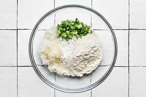 flour, baking powder, green onions, and Parmesan in a bowl to use for zucchini fritter batter
