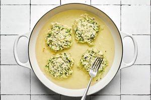 A skillet filled with sizzling oil, actively cooking several zucchini fritters until golden-brown with crispy edges