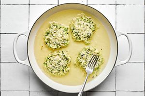 A skillet filled with sizzling oil, actively cooking several zucchini fritters until golden-brown with crispy edges
