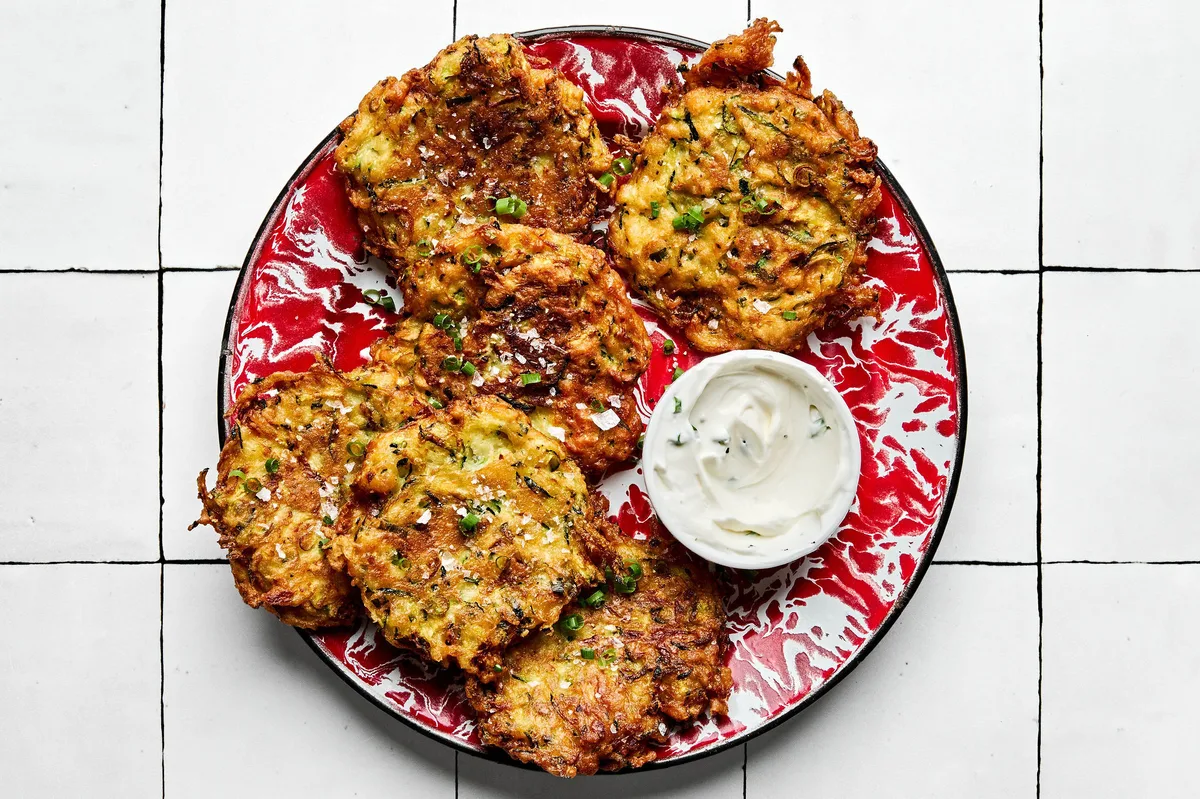 golden-brown homemade zucchini fritters with perfectly crispy on the edges on a plate served with sour cream