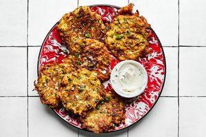 golden-brown homemade zucchini fritters with perfectly crispy on the edges on a plate served with sour cream