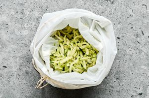 grated zucchini being strained in cheesecloth to draw out all the moisture before cooking