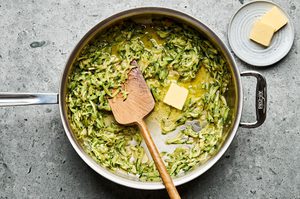 grated zucchini being cooked in a pan with butter, olive oil, garlic, salt, pepper and lemon zest to make zucchini pasta