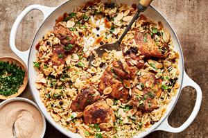 Almond and Currant Pilaf with Chicken in a skillet with a serving spoon