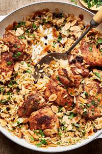 Almond and Currant Pilaf with Chicken in a skillet with a serving spoon