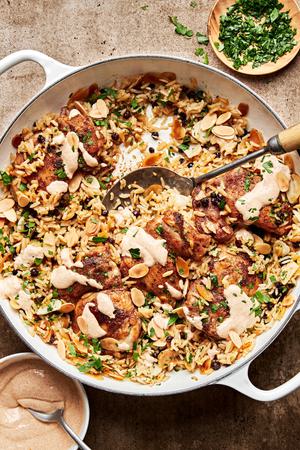 Almond and Currant Pilaf with Chicken in a skillet with a serving spoon