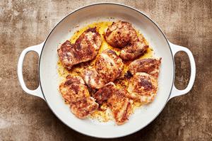 chicken thighs seasoned with salt, garlic powder, paprika, cumin and cinnamon being cooked in a skillet with olive oil