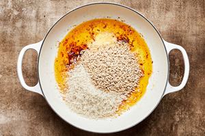 rice and orzo being cooked in butter in a skillet