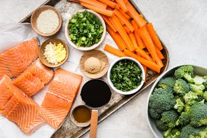 Ingredients laid out for a sheet pan dinner. Salmon, carrots, broccoli teriyaki sauce