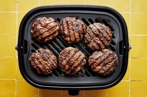 6 grilled beef patties on a grill