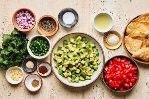 avocado, tomato, red onion, jalapeño, cilantro, lime juice, spices and tortilla chips in prep bowls
