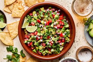 avocado salsa made with tomato, red onion, jalapeño, cilantro, lime juice and spices surrounded by tortilla chips