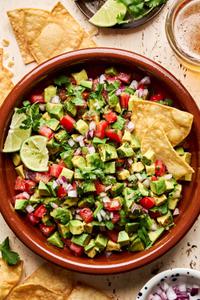avocado salsa made with tomato, red onion, jalapeño, cilantro, lime juice and spices surrounded by tortilla chips