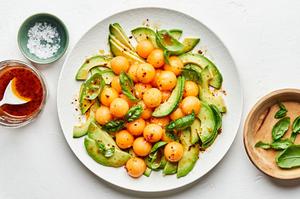 avocado and melon salad with fresh basil and drizzled with homemade dressing on a serving platter