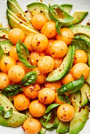 avocado and melon salad with fresh basil and drizzled with homemade dressing on a serving platter