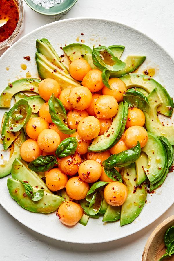 avocado and melon salad with fresh basil and drizzled with homemade dressing on a serving platter