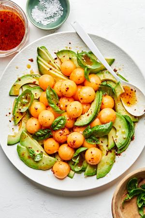 avocado and melon salad with fresh basil and drizzled with homemade dressing on a serving platter
