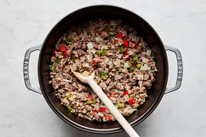 browned ground beef, pork, onion, peppers, garlic, salt, and pepper being cooked in a large soup pot