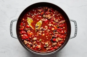 homemade chili in a soup pot made with beef, pork, black, pinto and kidney beans, onion, bell peppers and spices
